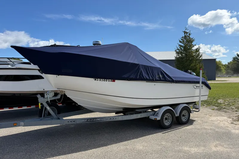 Slide: The Image of 2000 Boston Whaler 21 Outrage boat on trailer with cover, parked outdoors. - 19