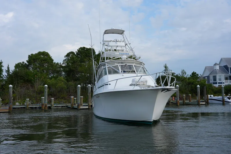 The Image of A 1999 Ocean Yachts 40 Super Sport is docked in the water, surrounded by trees and docks. - 0