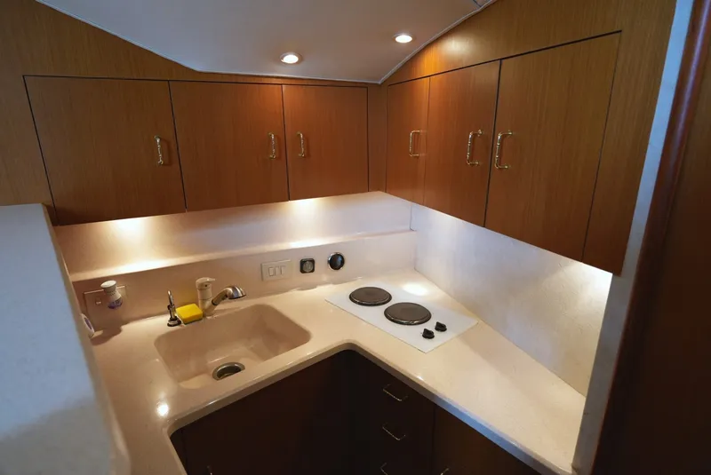 Slide: The Image of Compact kitchen with wooden cabinets, sink, and two burners. Elegant lighting and modern amenities. - 21