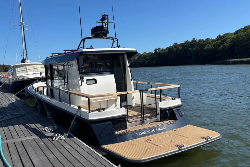 Slide: The Image of 2024 Targa 32 boat docked by a serene river, featuring a spacious deck. - 16