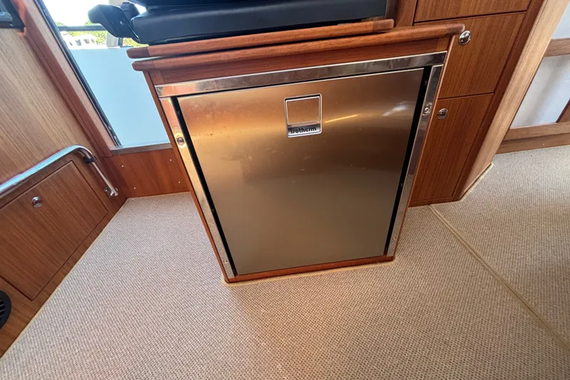 Slide: The Image of Stainless steel fridge in 2024 Targa 32 boat interior, featuring wooden cabinetry. - 33