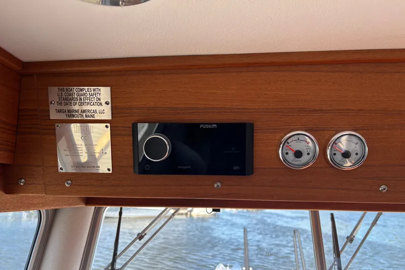 Slide: The Image of 2024 Targa 32 boat dashboard with gauges and safety compliance plaques. - 43