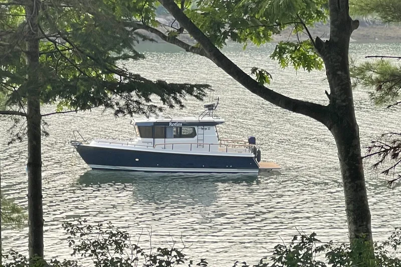 Slide: The Image of 2024 Targa 32 boat on a serene lake, framed by lush trees. - 6
