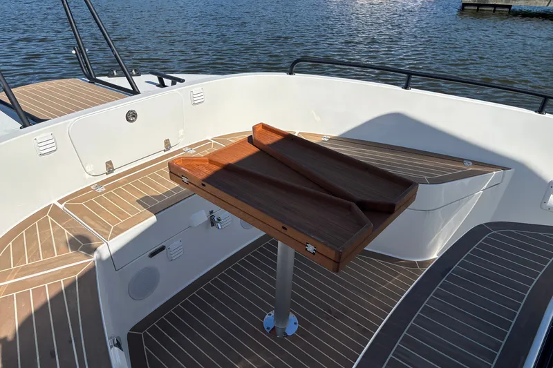 Slide: The Image of 2024 Targa 32 boat deck with wooden table, featuring sleek design and water backdrop. - 23