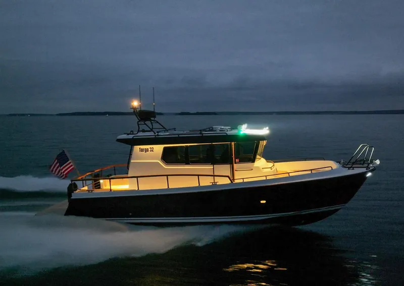 Slide: The Image of 2024 Targa 32 cruising at dusk, illuminated lights, with a flag at the stern. - 4