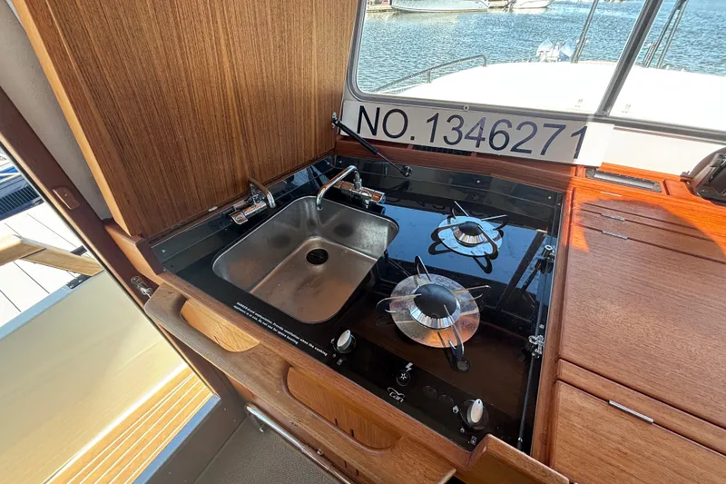 Slide: The Image of 2024 Targa 32 boat kitchen with stove and sink, docked by the water. - 32