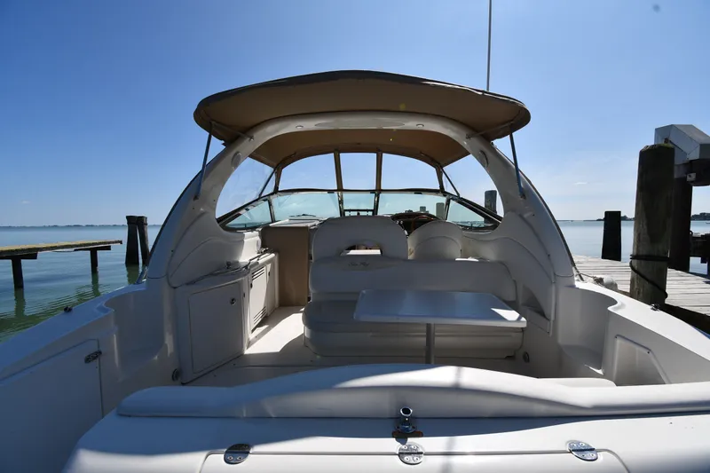 Slide: The Image of 2002 Sea Ray 360 Sundancer boat interior with seating and table, docked by calm waters. - 8
