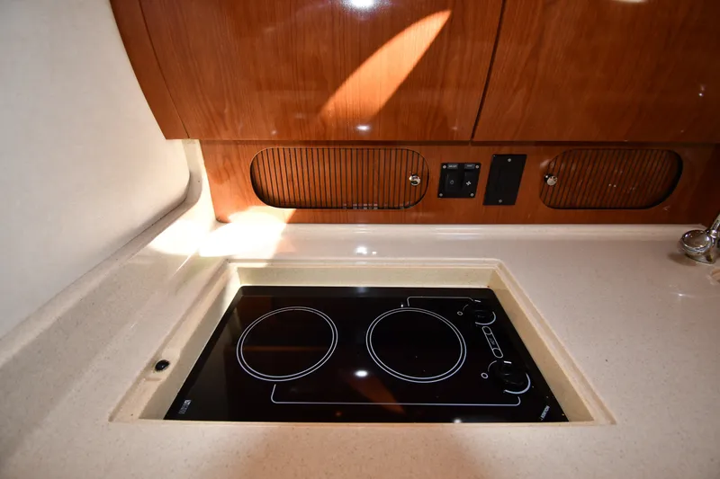 Slide: The Image of 2002 Sea Ray 360 Sundancer galley with electric cooktop and wooden cabinetry. - 30