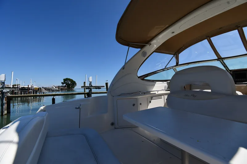 Slide: The Image of 2002 Sea Ray 360 Sundancer yacht interior with seating and table, docked by calm waters. - 14