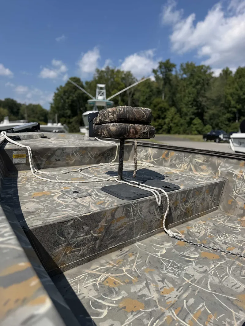 Slide: The Image of A War Eagle 2170 Blackhawk boat with a camouflaged seat on the deck, surrounded by trees. - 4