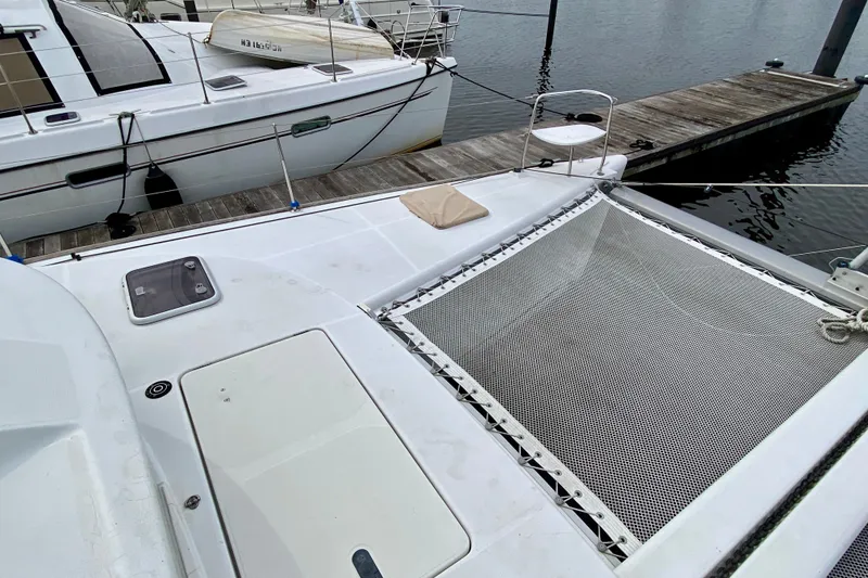 Slide: The Image of 2005 Lagoon 380 S2 catamaran docked, featuring deck and netting area. - 24