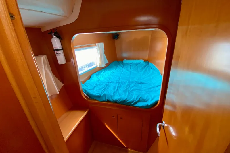 Slide: The Image of Cozy cabin interior of 2005 Lagoon 380 S2 catamaran with blue bedding and wooden finish. - 88