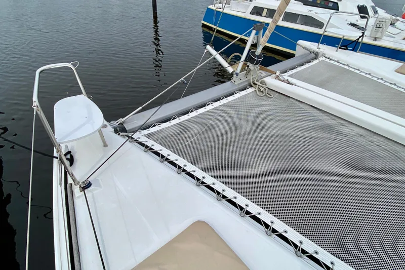 Slide: The Image of 2005 Lagoon 380 S2 catamaran deck with netting, docked on calm water. - 25