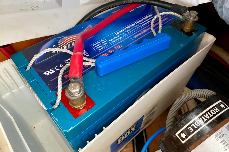 Slide: The Image of Battery installation in a 2005 Lagoon 380 S2 sailboat, featuring red and black cables. - 142