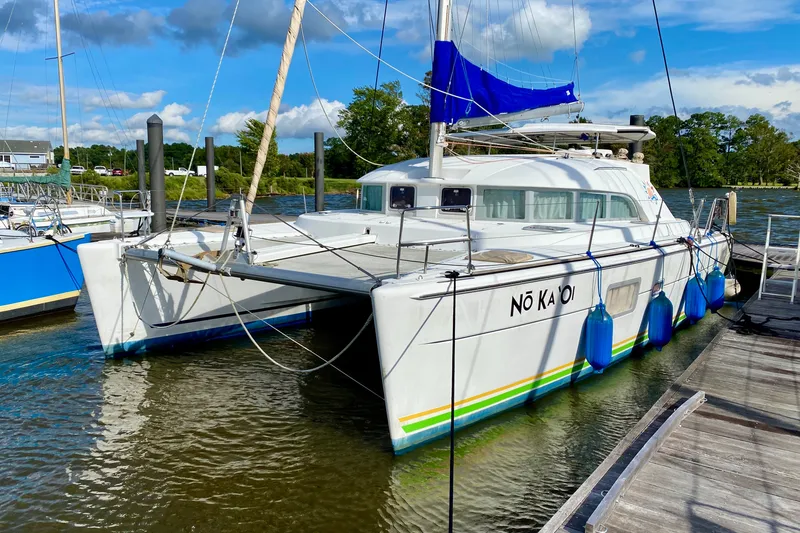 The Image of 2005 Lagoon 380 S2 catamaran docked at marina under blue sky. - 0