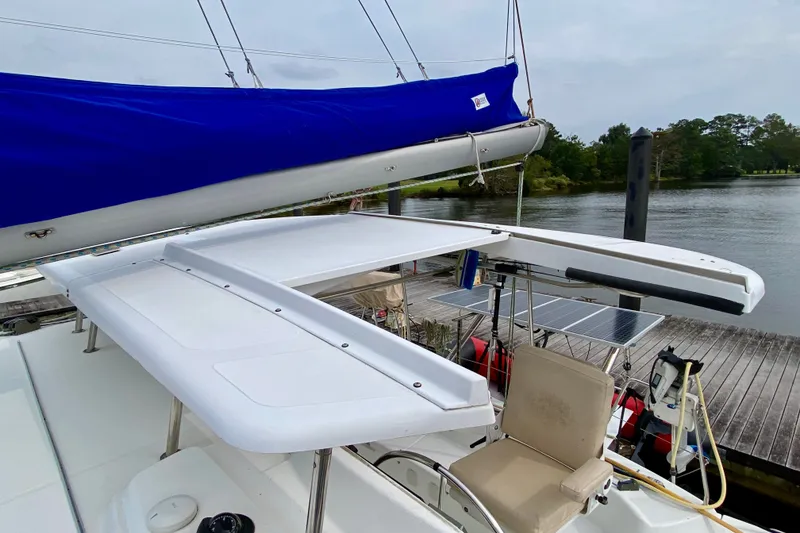 Slide: The Image of 2005 Lagoon 380 S2 catamaran with blue sail cover, docked by a serene waterfront. - 29