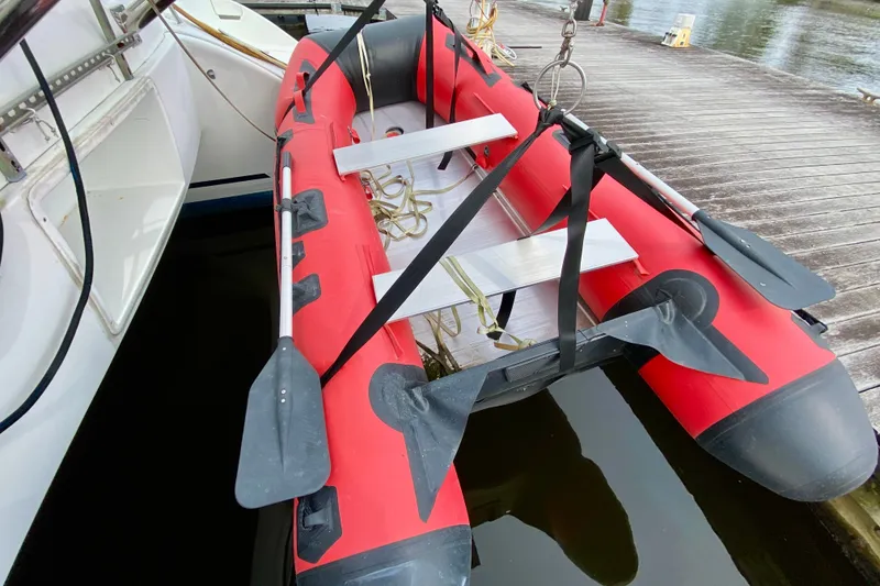 Slide: The Image of Red inflatable dinghy secured beside a 2005 Lagoon 380 S2 catamaran at a dock. - 155