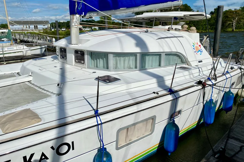 Slide: The Image of 2005 Lagoon 380 S2 catamaran docked with blue fenders and vibrant logo. - 1