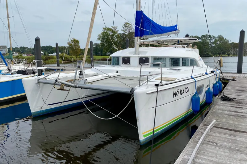 Slide: The Image of 2005 Lagoon 380 S2 catamaran docked, featuring blue fenders and a vibrant sail. - 1