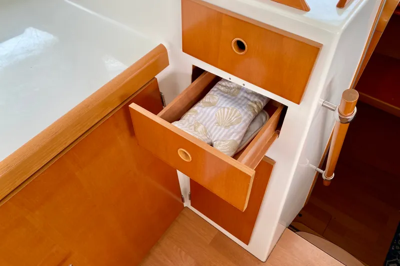 Slide: The Image of Open wooden drawer in 2005 Lagoon 380 S2 yacht interior, showing seashell-patterned fabric. - 129