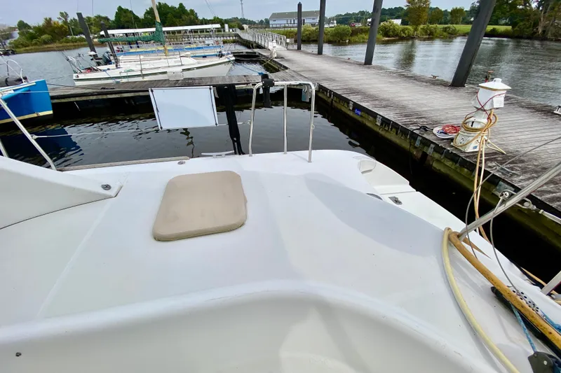 Slide: The Image of 2005 Lagoon 380 S2 catamaran docked at a marina, showcasing deck and surrounding water. - 36