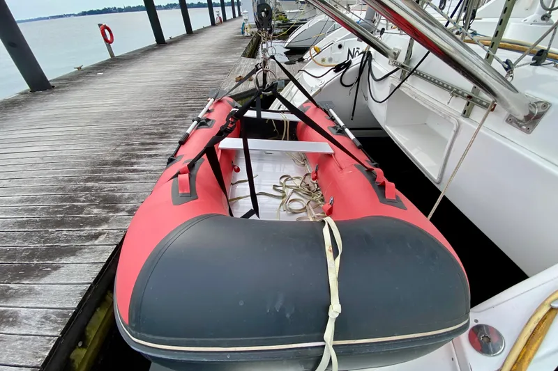 Slide: The Image of Red inflatable boat docked beside a 2005 Lagoon 380 S2 catamaran. - 154