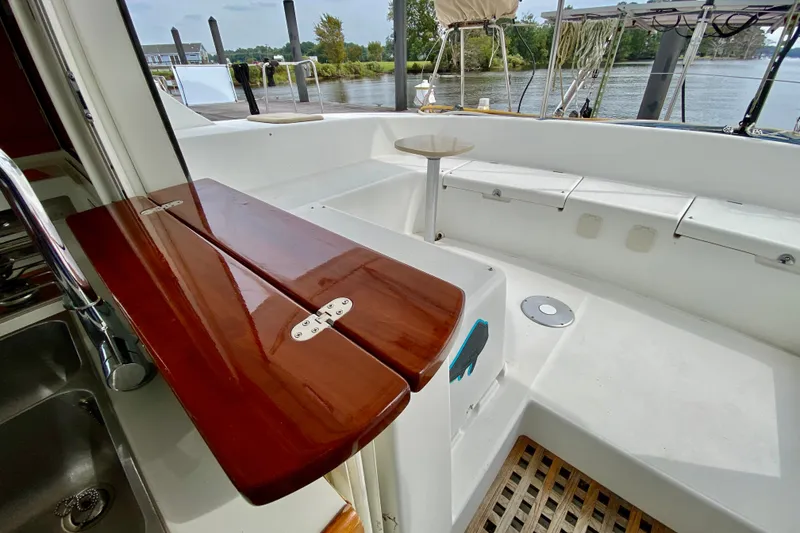 Slide: The Image of Cockpit of 2005 Lagoon 380 S2 catamaran with wooden table and scenic marina view. - 64