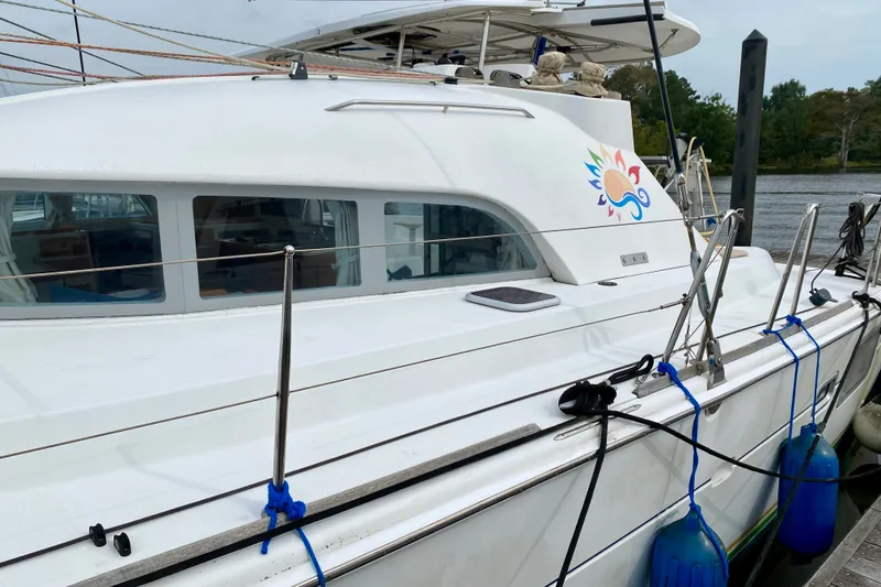 Slide: The Image of 2005 Lagoon 380 S2 catamaran docked, featuring sleek design and vibrant logo. - 9