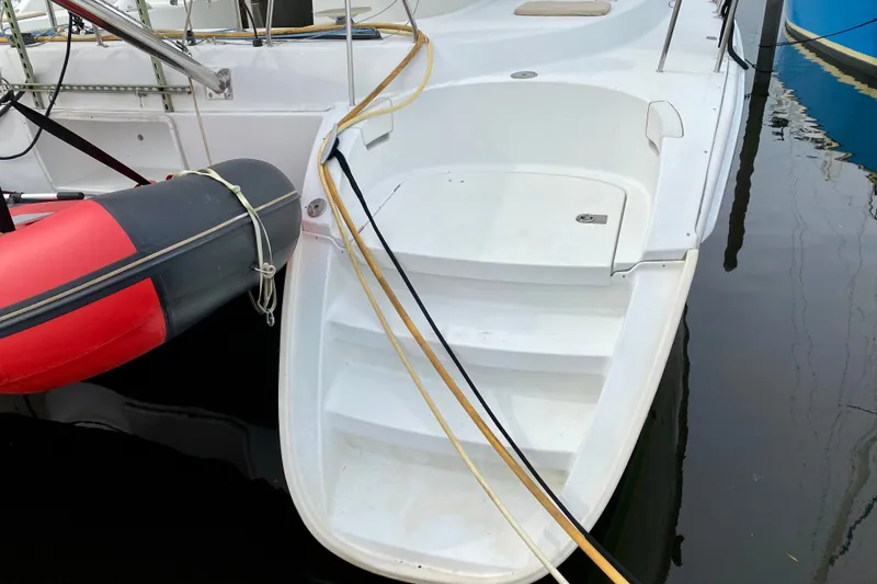 Slide: The Image of Lagoon 380 S2 catamaran stern with attached inflatable dinghy, docked in calm water. - 11