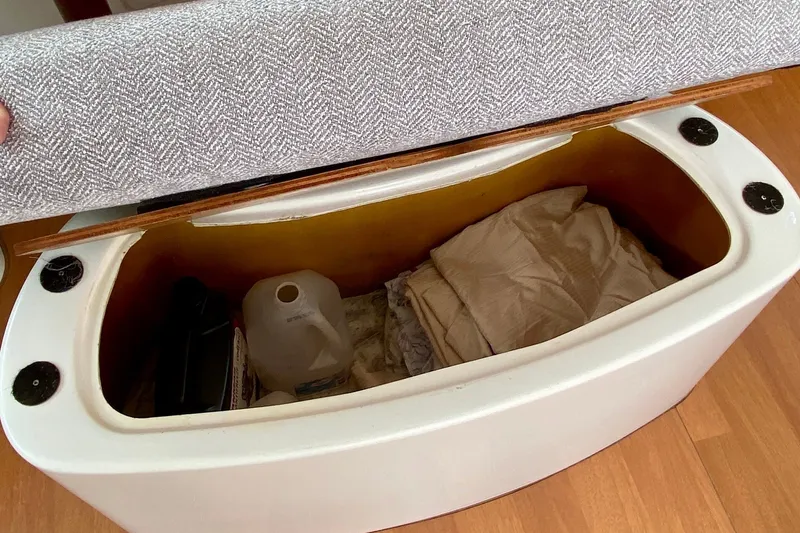 Slide: The Image of Storage compartment on a 2005 Lagoon 380 S2 yacht, containing folded fabric and a jug. - 136