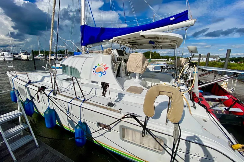 Slide: The Image of 2005 Lagoon 380 S2 catamaran docked, featuring blue sail cover and vibrant logo. - 3