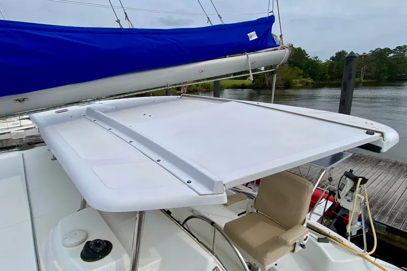 Slide: The Image of 2005 Lagoon 380 S2 sailboat with blue sail cover, docked by a serene river. - 30