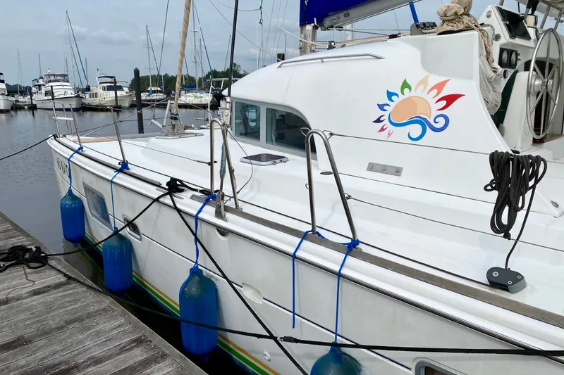 Slide: The Image of 2005 Lagoon 380 S2 catamaran docked at marina with colorful design on cabin. - 5