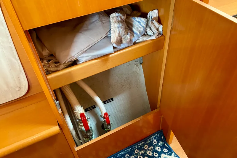 Slide: The Image of Open cabinet on Lagoon 380 S2 yacht, showing storage and plumbing, 2005 model. - 111