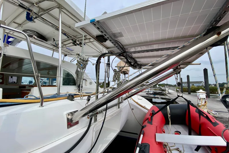 Slide: The Image of 2005 Lagoon 380 S2 catamaran docked, featuring solar panels and a red inflatable boat. - 152