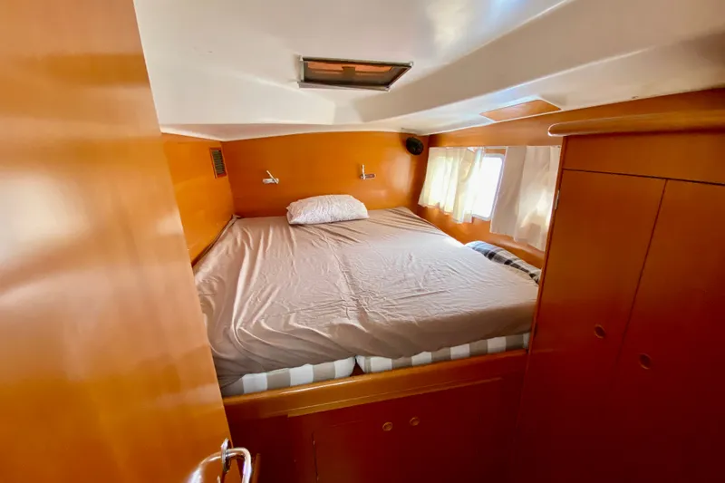 Slide: The Image of Cozy cabin interior of 2005 Lagoon 380 S2 catamaran with bed and wooden furnishings. - 92