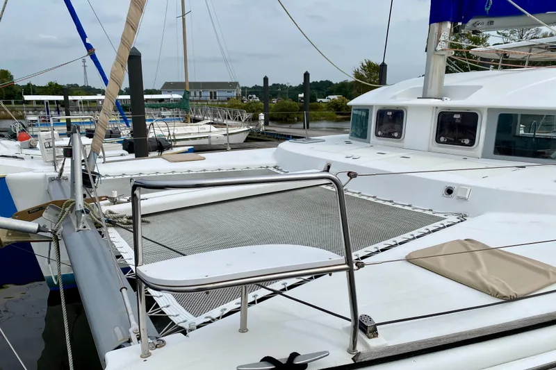 Slide: The Image of Catamaran Lagoon 380 S2, 2005 model, docked at marina with visible netting and deck. - 8