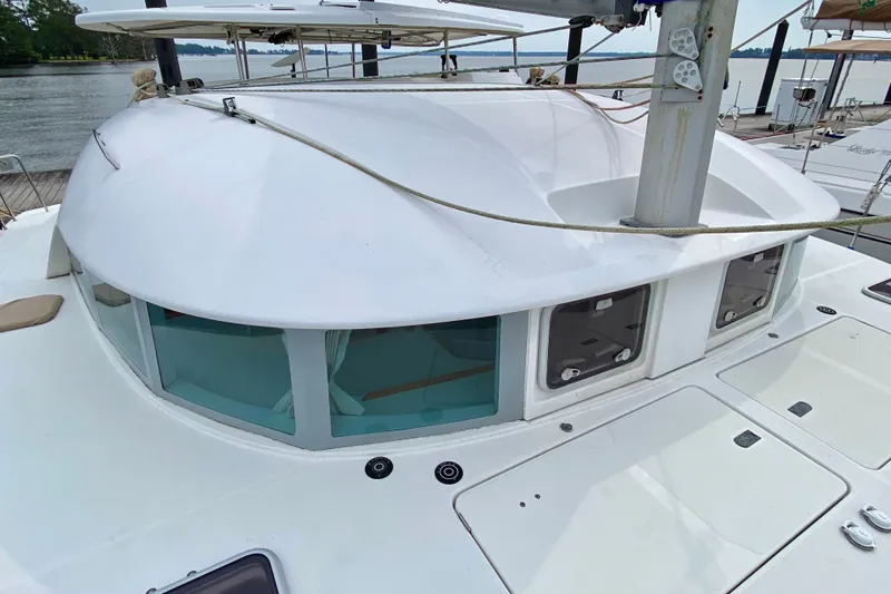 Slide: The Image of 2005 Lagoon 380 S2 catamaran deck with windows and mast, docked by the water. - 19
