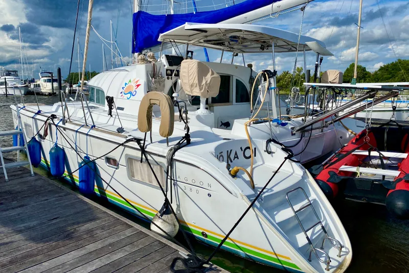 Slide: The Image of 2005 Lagoon 380 S2 catamaran docked at marina, featuring vibrant design and nautical equipment. - 2