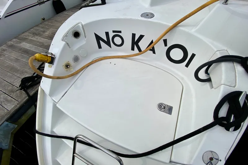 Slide: The Image of Stern view of 2005 Lagoon 380 S2 catamaran docked, featuring "Nō Ka 'Oi" text. - 102