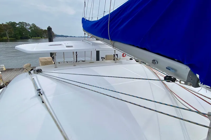 Slide: The Image of 2005 Lagoon 380 S2 catamaran with blue sail cover, docked by a serene river. - 20