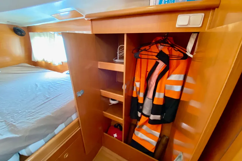 Slide: The Image of Cabin interior of 2005 Lagoon 380 S2 with bed and closet containing safety gear. - 115