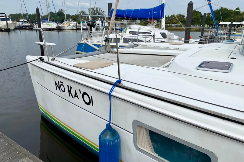 Slide: The Image of 2005 Lagoon 380 S2 catamaran docked at marina, named "Nō Ka 'Oi". - 6