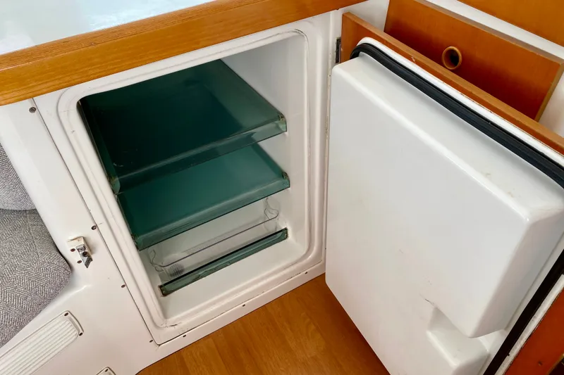Slide: The Image of Open refrigerator in 2005 Lagoon 380 S2 yacht, featuring glass shelves and wooden trim. - 132