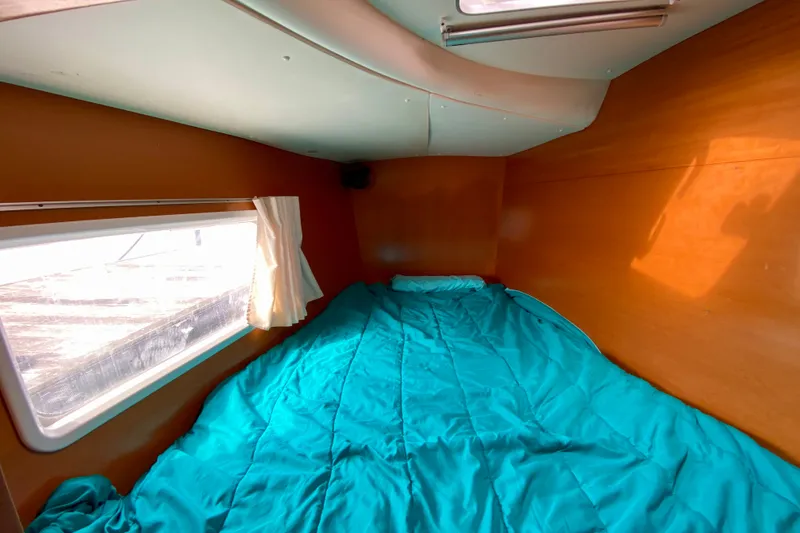 Slide: The Image of Cozy cabin interior of 2005 Lagoon 380 S2 catamaran with teal bedding and window view. - 89