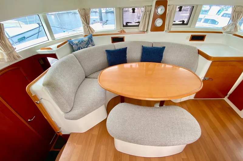 Slide: The Image of Cozy dining area in 2005 Lagoon 380 S2 catamaran with curved seating and wooden table. - 57