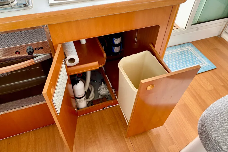 Slide: The Image of Interior of 2005 Lagoon 380 S2 yacht kitchen with open cabinet and trash bin. - 125