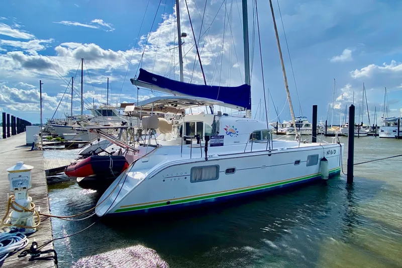 Slide: The Image of 2005 Lagoon 380 S2 catamaran docked at a marina under a partly cloudy sky. - 7
