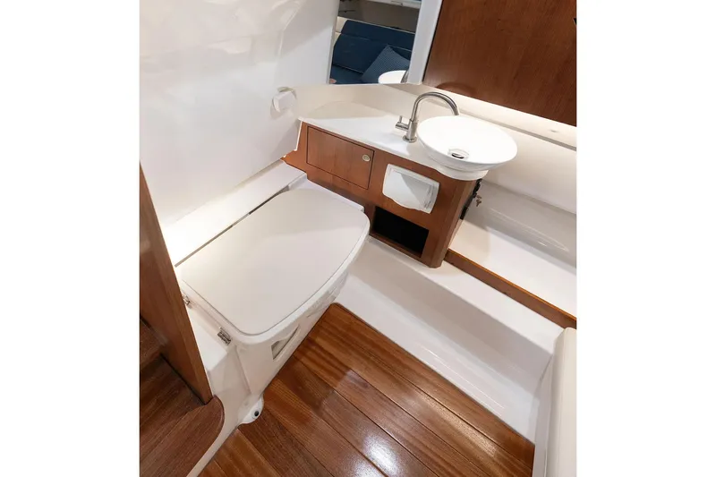 Slide: The Image of Manufacturer Provided Image: 2025 Pursuit S 328 Sport boat interior with wooden flooring and compact bathroom amenities. - 19