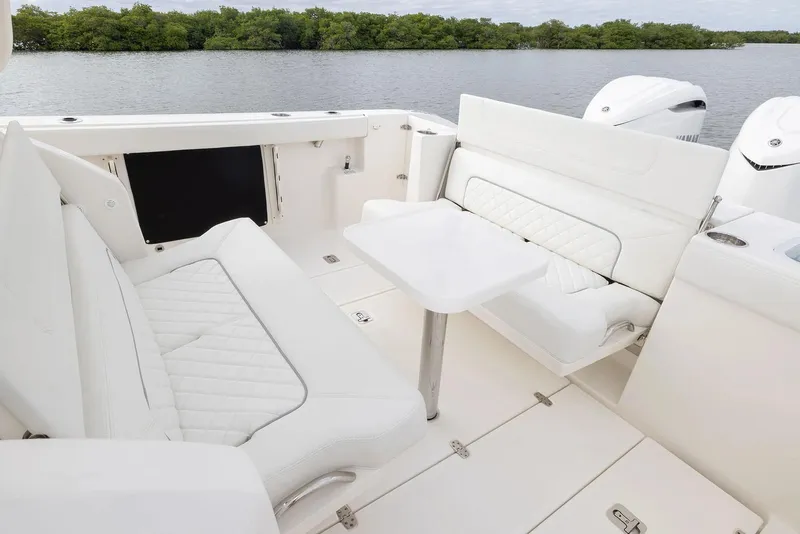 Slide: The Image of Manufacturer Provided Image: 2025 Pursuit S 328 Sport boat interior with white seating and table, near water. - 16